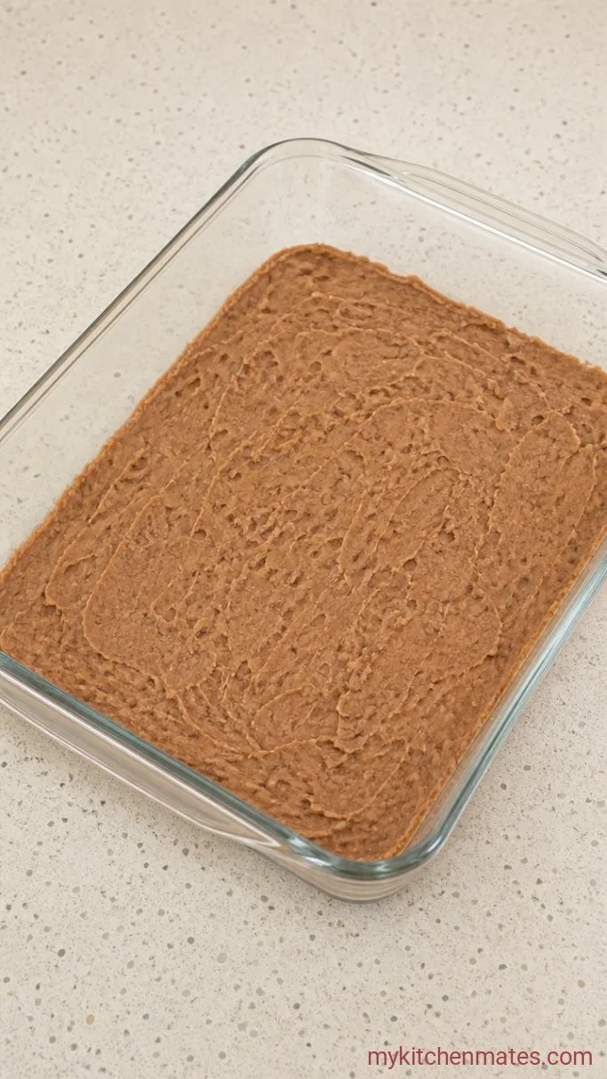 Seven-Layer Dip with Seasoned Ground Beef Step 2: Spread the Refried Beans